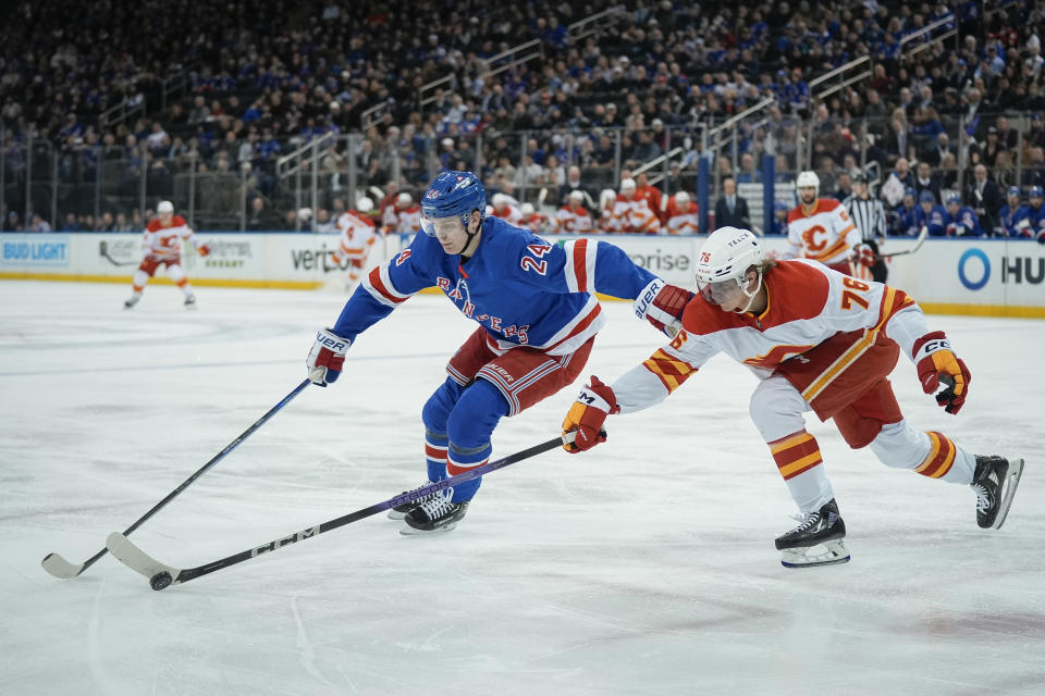 New York Rangers right wing Kaapo Kakko (24) and Calgary Flames center Martin Pospisil (76) battle for control of the puck during the first period an NHL hockey game on Monday, Feb. 12, 2024, in New York. (AP Photo/Bryan Woolston)