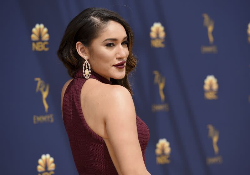 A side profile of a woman with dark hair in a sleeveless burgundy dress