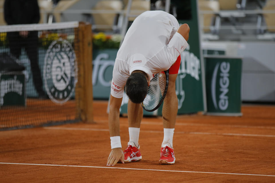Serbia's Novak Djokovic touches the clay court after winning his first round match of the French Open tennis tournament against Sweden's Mikael Ymer at the Roland Garros stadium in Paris, France, Tuesday, Sept. 29, 2020. (AP Photo/Michel Euler)