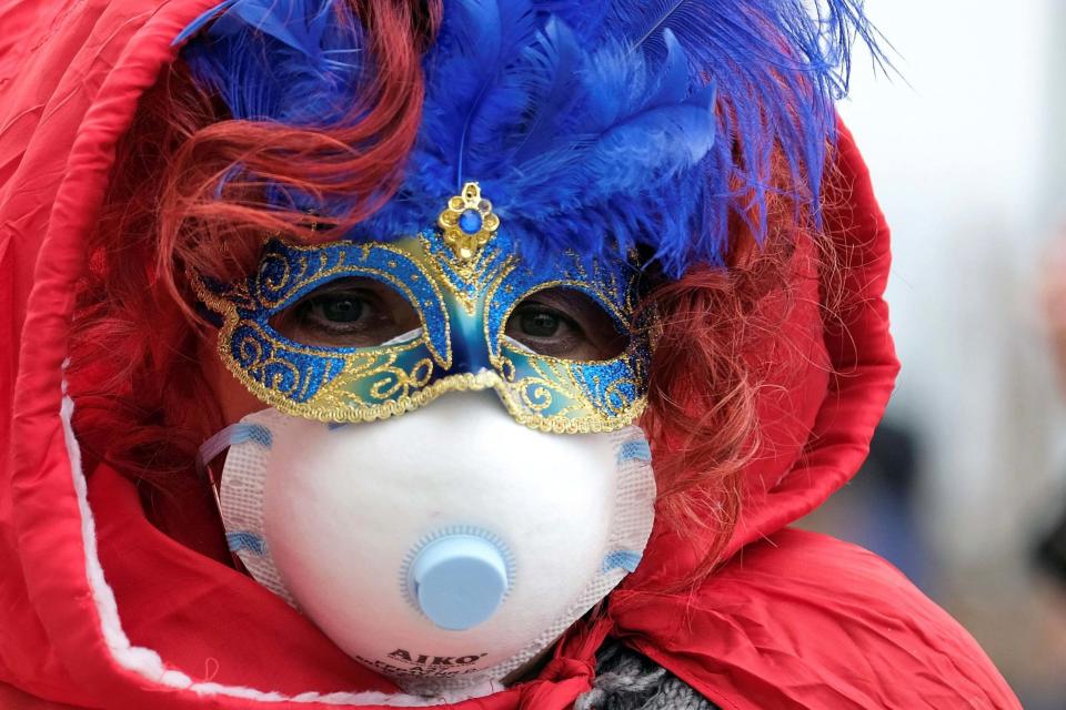 Masked carnival reveller wears protective face mask at Venice Carnival, which the last two days of, as well as Sunday night's festivities, have been cancelled (REUTERS)