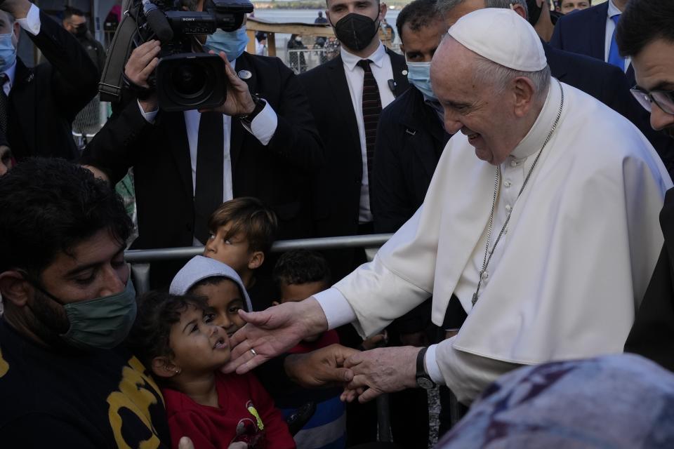 Pope Francis meets migrants during his visit at the Karatepe refugee camp, on the northeastern Aegean island of Lesbos, Greece, Sunday, Dec. 5, 2021. Pope Francis is offering comfort migrants at a refugee camp on the Greek island of Lesbos. He is blasting what he says is the indifference and self-interest shown by Europe "that condemns to death those on the fringes." (AP Photo/Alessandra Tarantino)