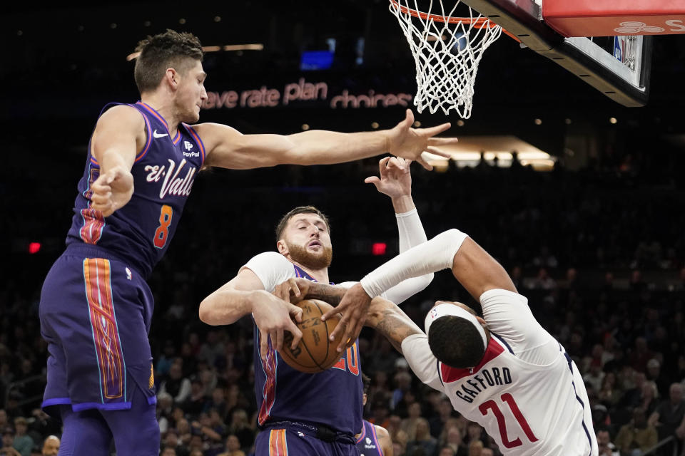 Phoenix Suns' Grayson Allen (8) and Just Nurkic, center, double-team Washington Wizards' Daniel Gafford (21) during the second half of an NBA basketball game in Phoenix, Sunday, Dec. 17, 2023. (AP Photo/Darryl Webb)