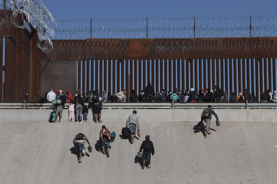 Migrants approach the border wall in Ciudad Juarez, Mexico, Wednesday, Dec. 21, 2022, on the other side of the border from El Paso, Texas. Migrants gathered along the Mexican side of the southern border Wednesday as they waited for the U.S. Supreme Court to decide whether and when to lift pandemic-era restrictions that have prevented many from seeking asylum. (AP Photo/Christian Chavez)