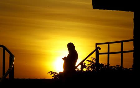 A Cuban migrant looks at a mobile phone as the sun sets in the town of La Cruz, Costa Rica, November 27, 2015. REUTERS/Juan Carlos Ulate