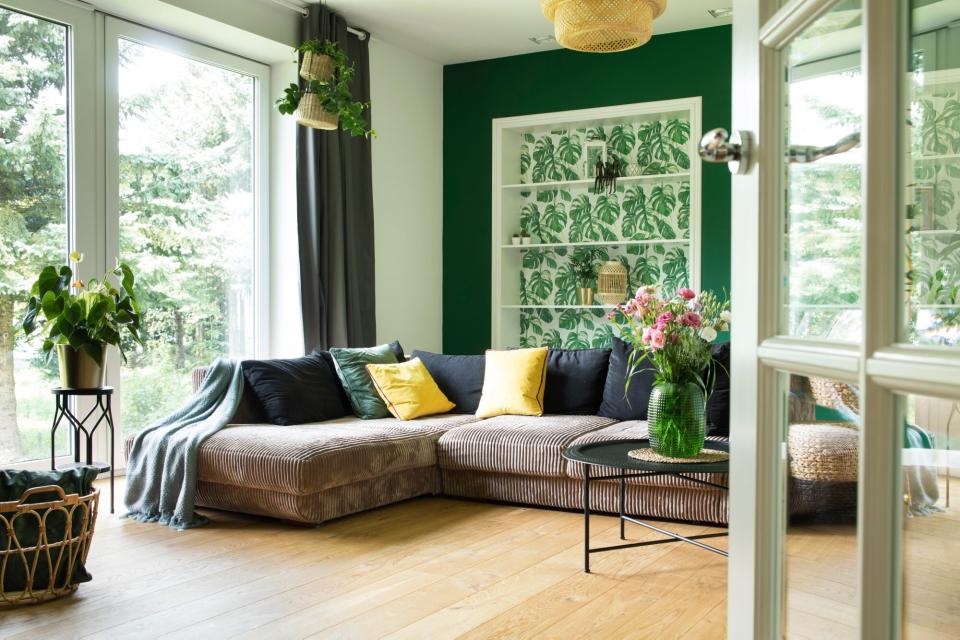 Modern and cozy living room with corduroy sofa, pillows, big window to the garden. Bright and sunny space.