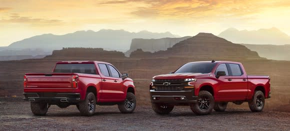 2 red 2019 Chevrolet Silverados, parked to display front and rear details, in a rugged desert setting.