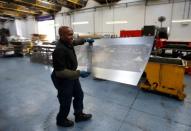 A worker at perforating company Bion carries a piece of perforated metal at the factory in Reading, Britain September 22, 2016. Picture taken September 22, 2016. To match Insight BRITAIN-EU/INVESTMENT REUTERS/Peter Nicholls