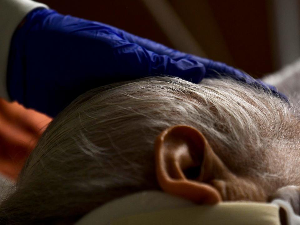 Michelle Kilian, an ICU nurse at Providence Holy Cross Medical Center, holds a patient's head after brushing and braiding their hair on Tuesday, Feb. 9, 2021, in Los Angeles. "We prone them so much that their just hair gets clumped up," Kilian said. "If I have some time I try to brush it so it doesn't become one tangled mess, because if that was my mom, that's what I would want them to do."