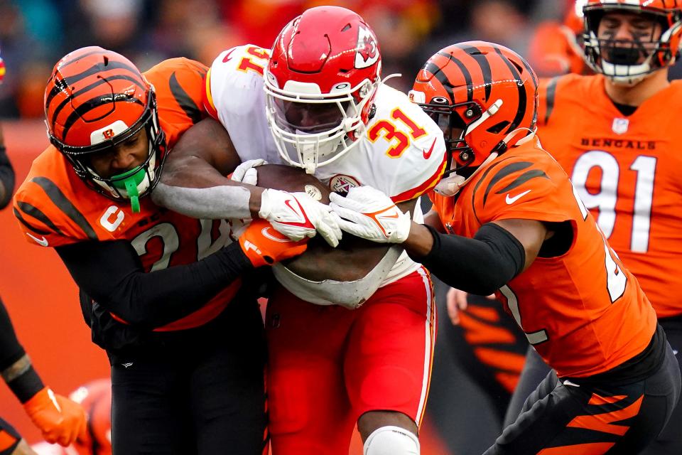 Kansas City Chiefs running back Darrel Williams (31) carries the ball as Cincinnati Bengals safety Vonn Bell (24), left, and Cincinnati Bengals cornerback Chidobe Awuzie (22), right, defend in the third quarter during a Week 17 NFL game, Sunday, Jan. 2, 2022, at Paul Brown Stadium in Cincinnati. The Cincinnati Bengals defeated the Kansas City Chiefs, 34-31. With the win the, the Cincinnati Bengals won the AFC North division and advance to the NFL playoffs. 