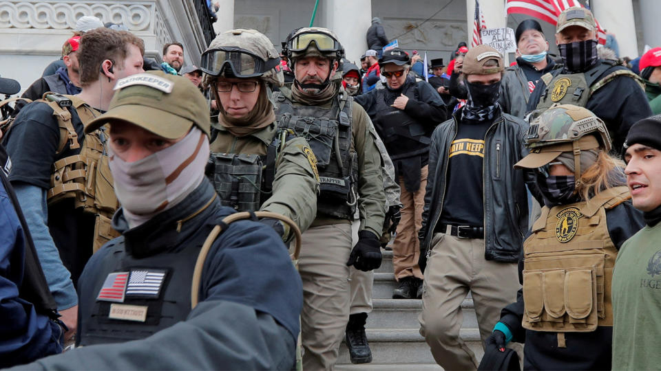 Members of the Oath Keepers militia group, left, march down Capitol steps among supporters of Donald Trump, Jan. 6, 2021