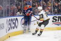 Vegas Golden Knights' Shea Theodore (27) and Edmonton Oilers' Zach Hyman (18) compete for the puck during the second period of an NHL hockey game Saturday, March 25, 2023, in Edmonton, Alberta. (Jason Franson/The Canadian Press via AP)