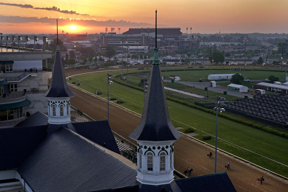 Horses work out as the sun rises at Churchill Downs Friday, April 30, 2021, in Louisville, Ky. The 147th running of the Kentucky Derby is scheduled for Saturday, May 1. (AP Photo/Charlie Riedel)