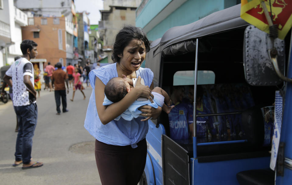 FILE - In this Monday, April 22, 2019 file photo, a Sri Lankan woman, who lives near St. Anthony's shrine, runs for safety with her infant after police found explosive devices in a parked vehicle in Colombo, Sri Lanka. (AP Photo/Eranga Jayawardena)
