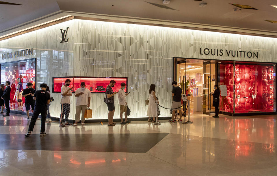 Patrons stand in a line to enter the Louis Vuitton shop at the upmarket shopping mall Siam Paragon in Bangkok, Thailand, Sunday, May 17, 2020. Thai authorities allowed department stores, shopping malls and other businesses to reopen from Sunday, selectively easing restrictions meant to combat the coronavirus. (AP Photo/ Gemunu Amarasinghe)