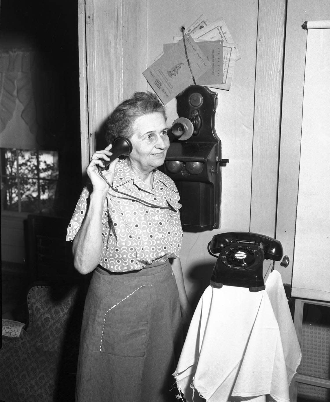 Aug. 5, 1954: Mrs. Mabel Scott of Keller makes a call on old-time magneto wall telephone. Fort Worth Star-Telegram archive/UT Arlington Special Collections