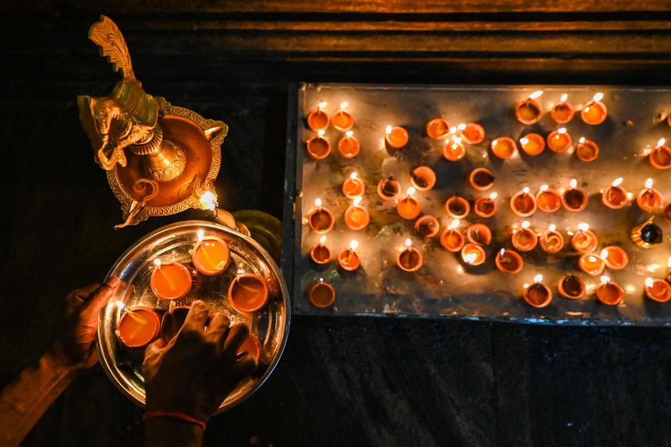 A devotee holds an oil lamp while offering prayers during the Hindu festival of Diwali at a temple in Sri Lanka on Monday.