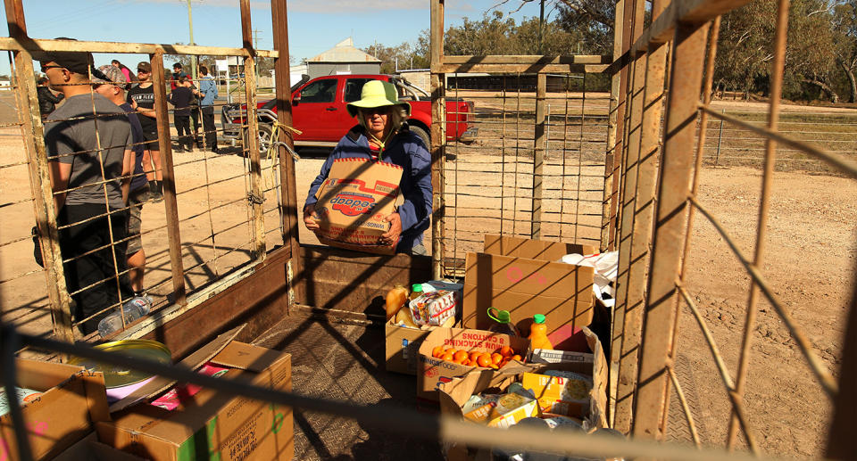 Local resident Bessie Lambert is seen loading a trailer with food and water aid in Mungindi during the drought last year. Source: AAP