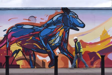 A builder walks past graffiti in Dublin, Ireland February 11, 2016. REUTERS/Clodagh Kilcoyne