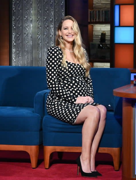 A pregnant Jennifer smiling as she sits for an interview on a late-night tv show