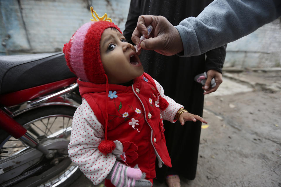 A health worker administers a polio vaccine to a child in Lahore, Pakistan, Monday, Jan. 24, 2022. Pakistani authorities on Monday launched this year's first nationwide anti-polio campaign despite facing a sudden surge of coronavirus cases in an effort aimed eradicating the crippling children's disease. (AP Photo/K.M. Chaudhry)