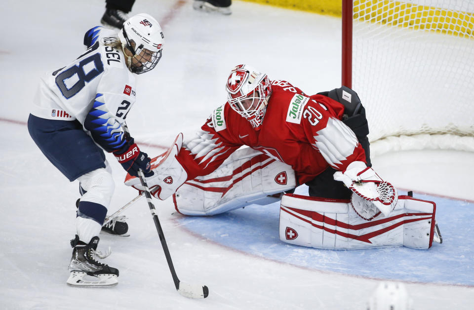 Switzerland goalie Andrea Braendli, right, blocks the net on United States' Amanda Kessel during the second period of an IIHF women's hockey championships game in Calgary, Alberta, Friday, Aug. 20, 2021. (Jeff McIntosh/The Canadian Press via AP)