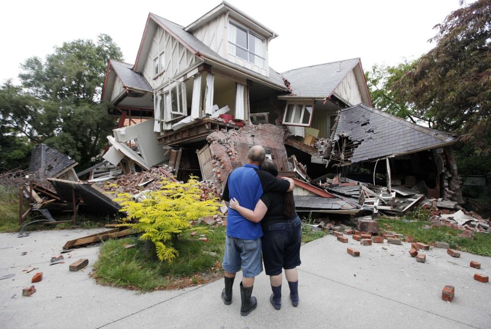 FILE - In this Feb. 23, 2011, file photo Murray, left, and Kelly James look at their destroyed house in central Christchurch, New Zealand, a day after a deadly earthquake. Despite its tranquility and beauty, New Zealand city of Christchurch is painfully familiar with trauma and will need to use that experience to recover from terrorist attack. (AP Photo/Mark Baker, File)