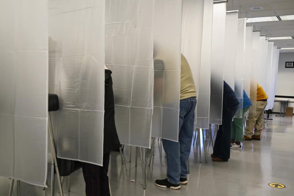 FILE - In this Oct. 6, 2020, file photo, voters fill out their ballot during early voting at the Cuyahoga County Board of Elections in Cleveland. A surge in coronavirus cases is hitting key presidential battleground states a little more than two weeks before Election Day, raising concerns that voting could be thrown into chaos despite months of preparation and planning by election officials and voters. (AP Photo/Tony Dejak, File)