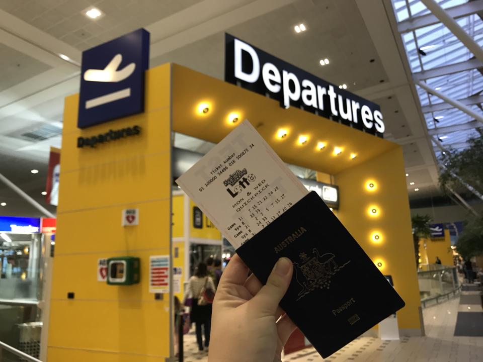 A file pic of a man holding an Oz Lotto ticket with a passport at the departure gate of an airport.