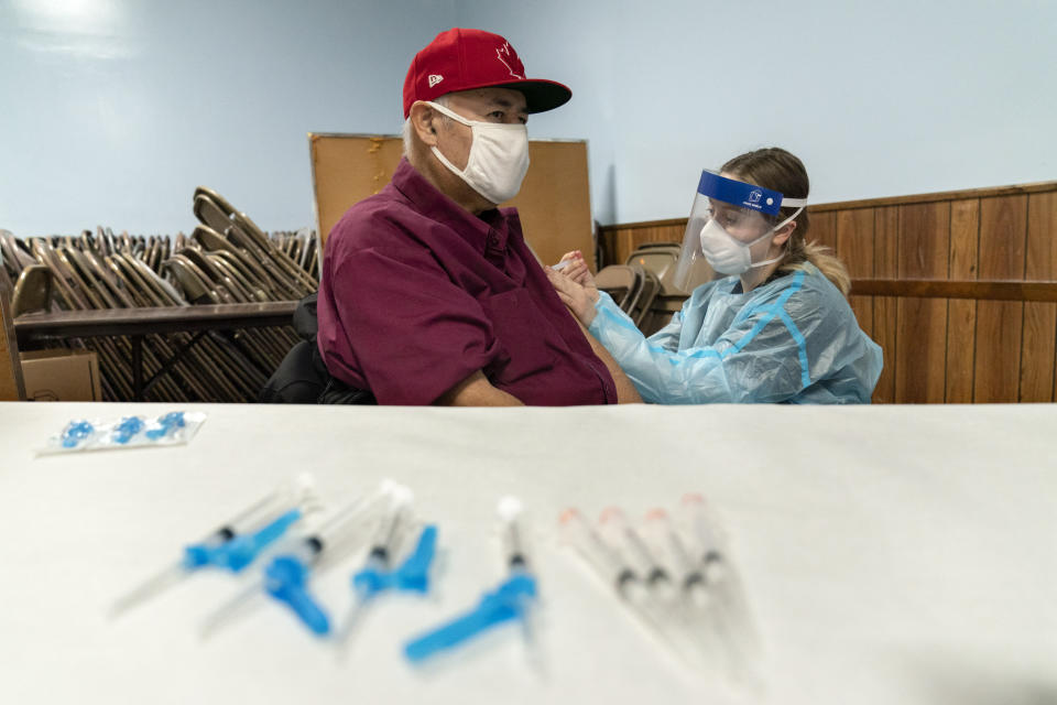 Mario Valdez, 62, receives his first shot of a vaccine at a clinic in Central Falls, R.I., Saturday, Jan. 9, 2021. "I feel happy," the 62-year-old school bus driver said shortly after receiving his second and final dose five weeks later. "Too many people here have COVID. It's better to be safe." (AP Photo/David Goldman)