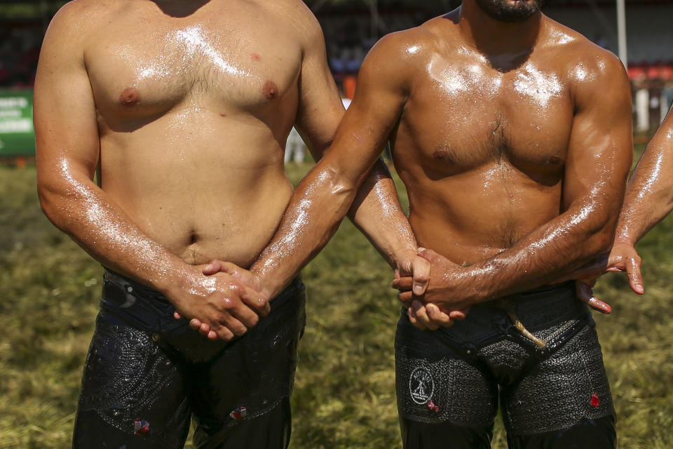 Wrestlers, doused in olive oil, greet each other as they are introduced to the crowds during the 660th instalment of the annual Historic Kirkpinar Oil Wrestling championship, in Edirne, northwestern Turkey, Saturday, July 10, 2021. Thousands of Turkish wrestling fans flocked to the country's Greek border province to watch the championship of the sport that dates to the 14th century, after last year's contest was cancelled due to the coronavirus pandemic. The festival, one of the world's oldest wrestling events, was listed as an intangible cultural heritage event by UNESCO in 2010. (AP Photo/Emrah Gurel)