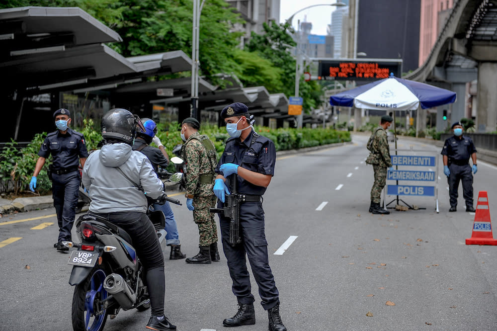 Soldiers and police officers conducting checks at a roadblock during the movement control order (MCO) in Kuala Lumpur March 29, 2020. — Picture by Firdaus Latif