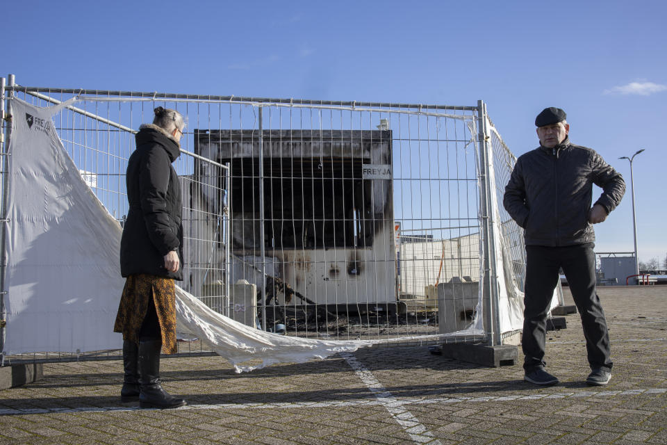 A person looks at a torched coronavirus testing facility in the Dutch fishing village of Urk, Sunday, Jan. 24, 2021, after it was set ablaze Saturday night by rioting youths protesting on the first night of a nation-wide curfew. (AP Photo/Peter Dejong)