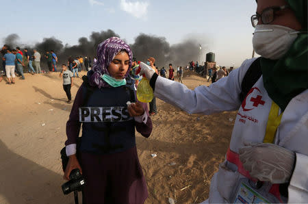 A female photojournalist is treated from tear gas during a protest where Palestinians demand the right to return to their homeland, at the Israel-Gaza border in the southern Gaza Strip May 25, 2018. REUTERS/Ibraheem Abu Mustafa