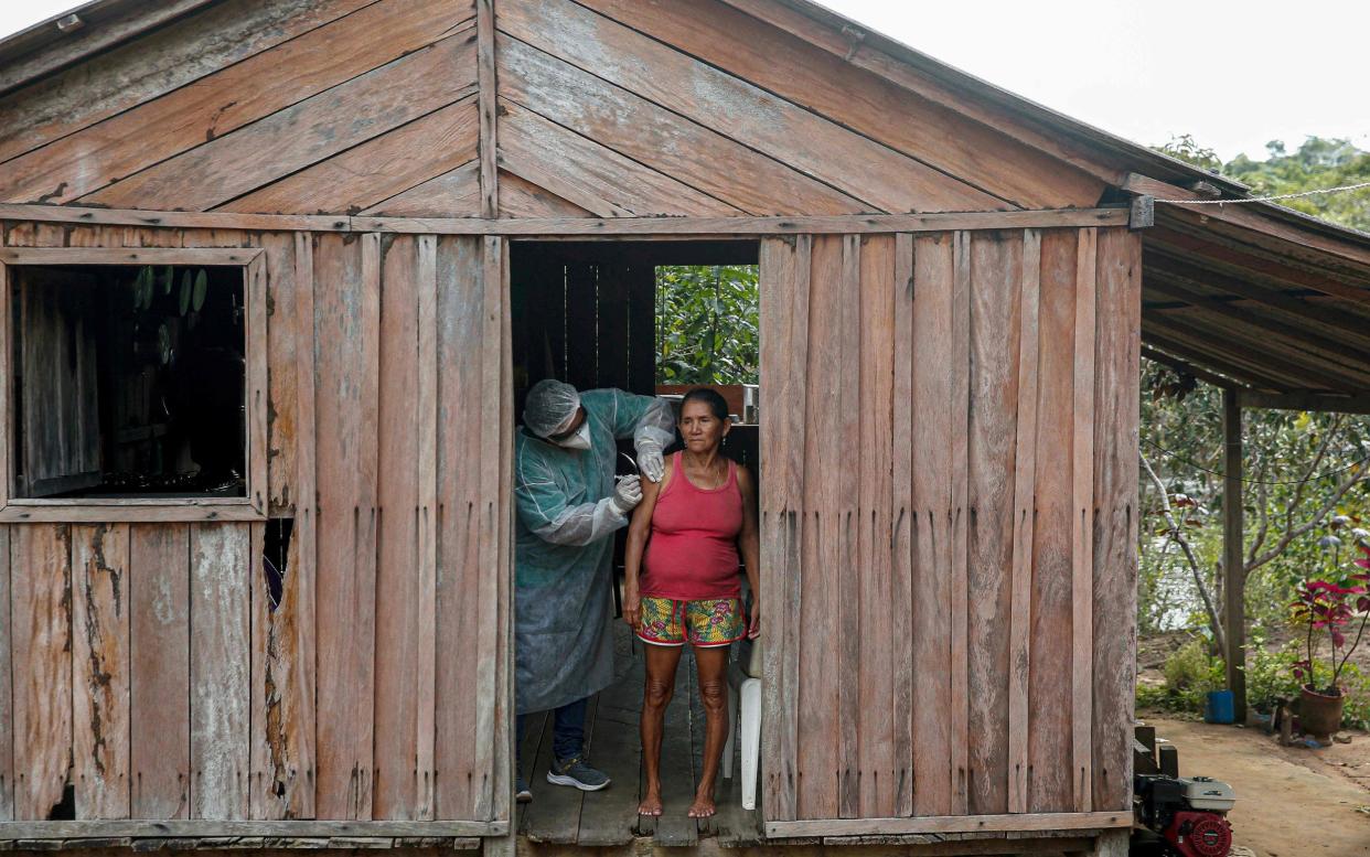 A health worker from the Ministry of Health Department for Indigenous Health adminsters a second dose of a COVID-19 vaccine to patient Maria Tereza in Sao Jose IIIÂ do rio Maro, in the Lower Amazon region of the state of Para, near Santarem in Brazil, on February 13, 2021 - Tarso SARRAF/AFP via Getty Images