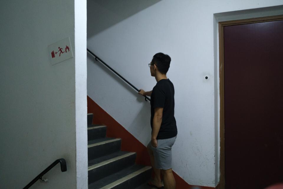 A man stands at the foot of a staircase