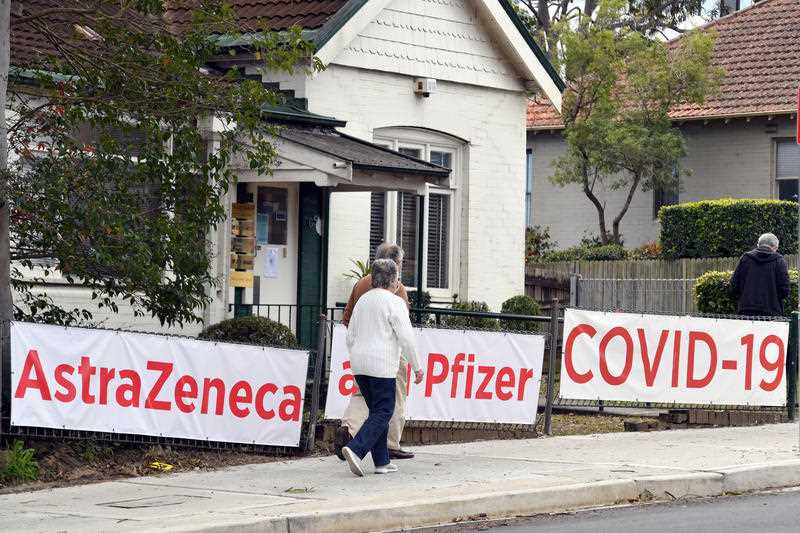 A couple walk past signs of AstraZeneca and Pfizer Covid-19 vaccines outside a doctor’s surgery in the lower north shore suburb of Lane Cove in Sydney.