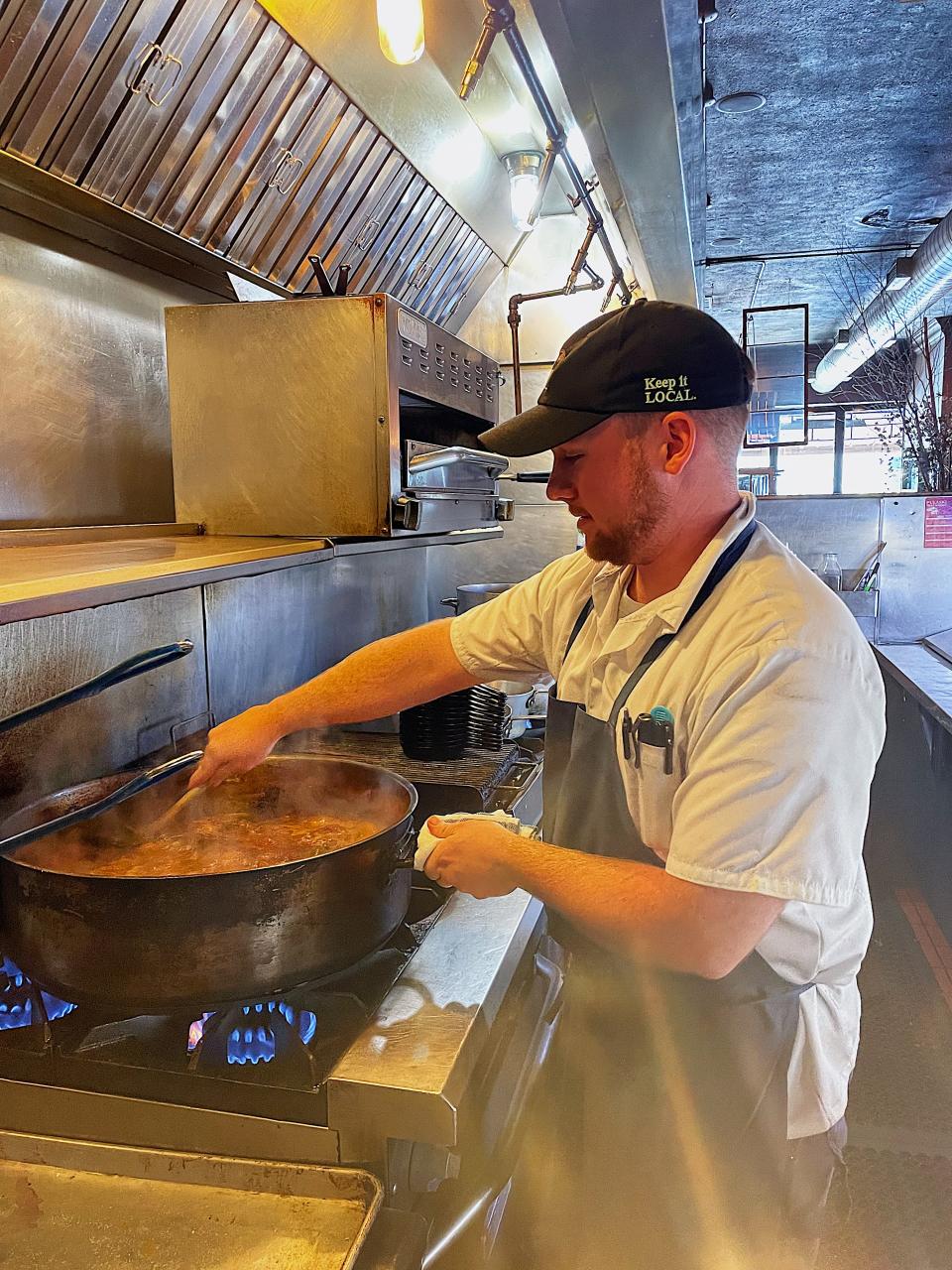 Cody Jipson stirs a huge pan of simmering tomatoes.