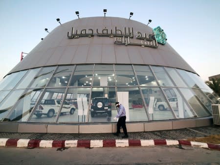 A worker cleans the front face of the car showroom of Abdul Latif Jamil Automobile, Saudi dealer for Toyota in Dhahran