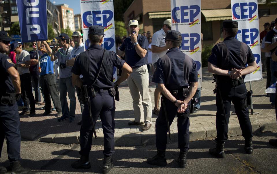 Varios policías inconformes con las medidas de austeridad en España protestan con silbatos frente a las instalaciones de una ceremonia de graduación de agentes en Madrid el martes 17 de julio de 2012. Otros policías resguardan el orden en el lugar, mientras el gobierno colocó deuda por 3.600 millones de euros. (Foto AP/Emilio Morenatti)