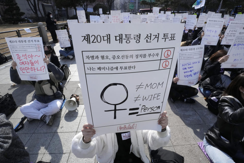 People stage a rally supporting feminism in Seoul, South Korea, Feb. 12, 2022. The signs at top read 