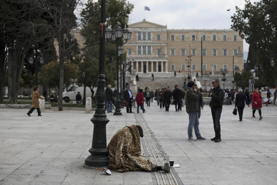 A homeless person begs in Syntagma square, backdropped by the Greek parliament, in central Athens, on Thursday, March 15, 2012. Countries in the 17-nation eurozone on Wednesday formally approved a second bailout for Greece and authorized the release of €39.4 billion ($51.44 billion), as they had signaled last week. (AP Photo/Petros Giannakouris)