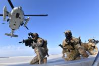 In this photo provided by South Korea's Navy, Members of South Korean Navy's special forces aim their weapons after landed from UH-60 helicopter during the drill on the islets called Dokdo in Korean and Takeshima in Japanese, Sunday, Aug. 25, 2019. In a development that could possibly further complicate ties between Seoul and Tokyo, South Korea's navy on Sunday began two-day exercises on and around a group of islets controlled by South Korea but also claimed by Japan. (South Korea's Navy via AP)