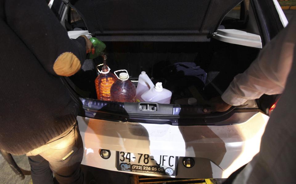 A driver fills containers in the trunk with gasoline after waiting for hours at a gas station in Valle de Bravo, Mexico, late Friday, Dec. 30, 2016. Most of the city's fill-up stations were closed on Friday night because they were out of fuel, and drivers waited up to three hours at this pump. On Jan. 1, Mexicans will start paying market prices for gasoline as part of a price deregulation, triggering gasoline shortages in many parts of the country. (AP Photo/Marco Ugarte)