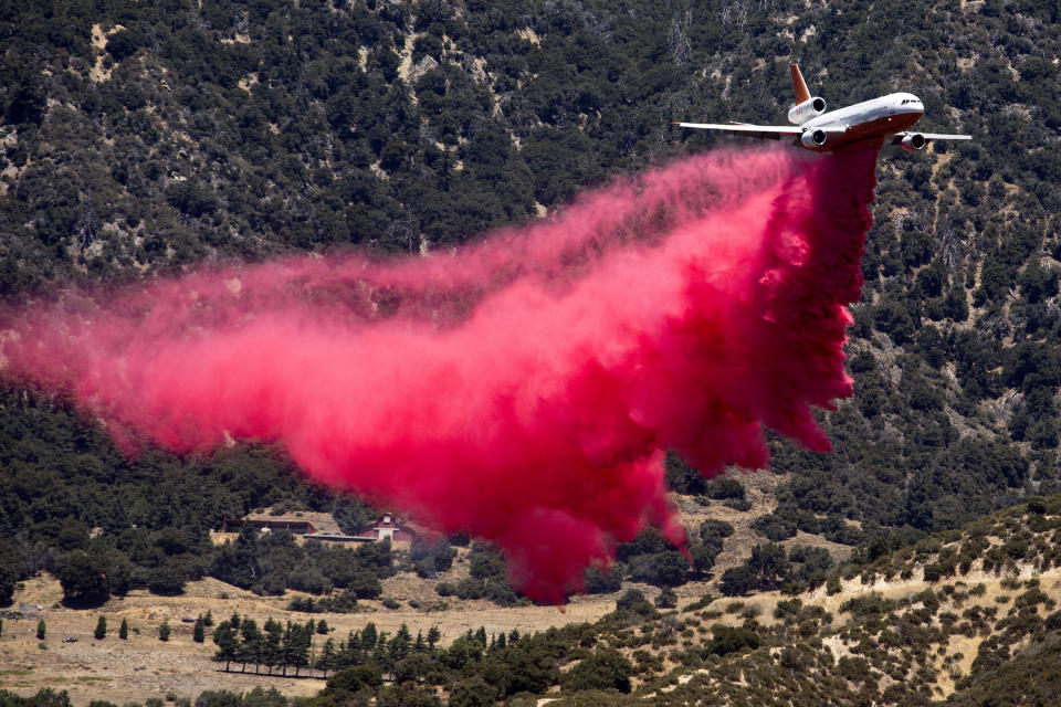 An air tanker drops fire retardant at the Apple Fire in Cherry Valley, Calif., Saturday, Aug. 1, 2020. A wildfire northwest of Palm Springs flared up Saturday afternoon, prompting authorities to issue new evacuation orders as firefighters fought the blaze in triple-degree heat. (AP Photo/Ringo H.W. Chiu)