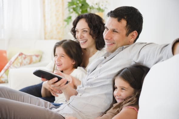 Happy family sitting on sofa watching television