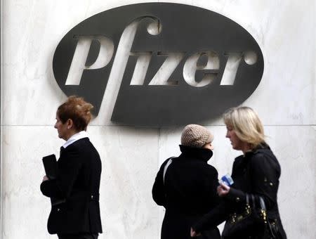 Pedestrians walk past the Pfizer logo on the exterior of their world headquarters in New York November 5, 2013. REUTERS/Adam Hunger