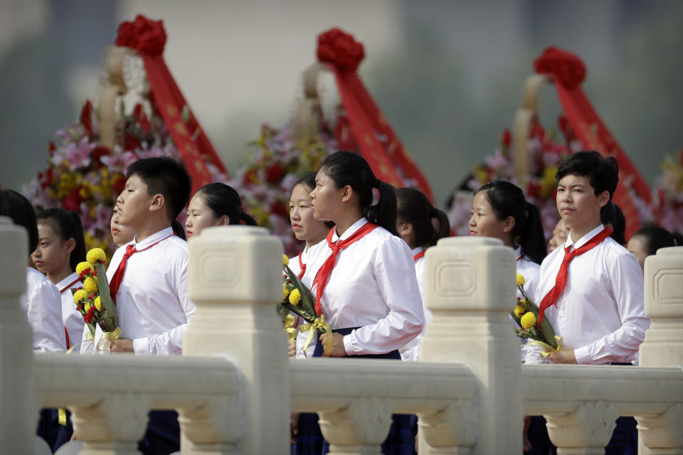 Schoolchildren carry flowers as they walk past floral wreaths at the Monument to the People's Heroes during a ceremony to mark Martyr's Day at Tiananmen Square in Beijing, Monday, Sept. 30, 2019, ahead of a massive celebration of the People's Republic's 70th anniversary. (AP Photo/Mark Schiefelbein, Pool)