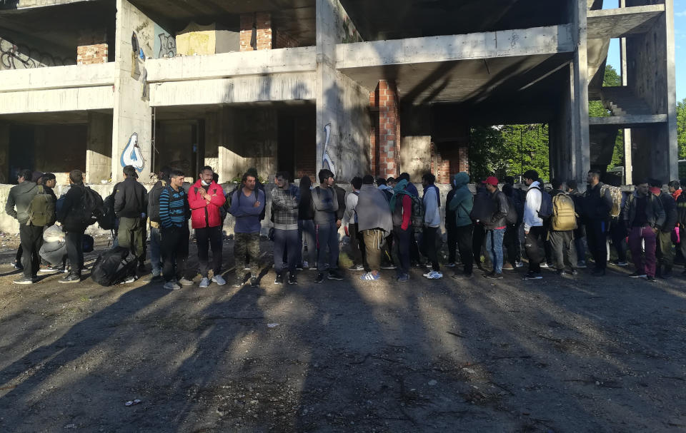 Migrants wait as they leave to be relocated from an abandoned building in Bihac, northwestern Bosnia, Tuesday, May 18, 2021. Bosnian police on Tuesday rounded up more than 200 migrants who were squatting in an abandoned building in a northern town and moved them to a nearby tent camp. (AP Photo/Hasan Arnautovic)