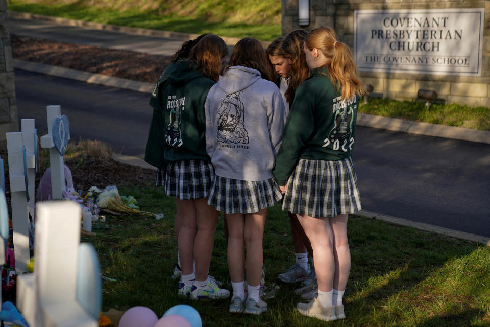 Students from the nearby Harpeth Hall School pray while visiting a memorial at the entrance of the Covenant School in Nashville, March 29, 2023. 