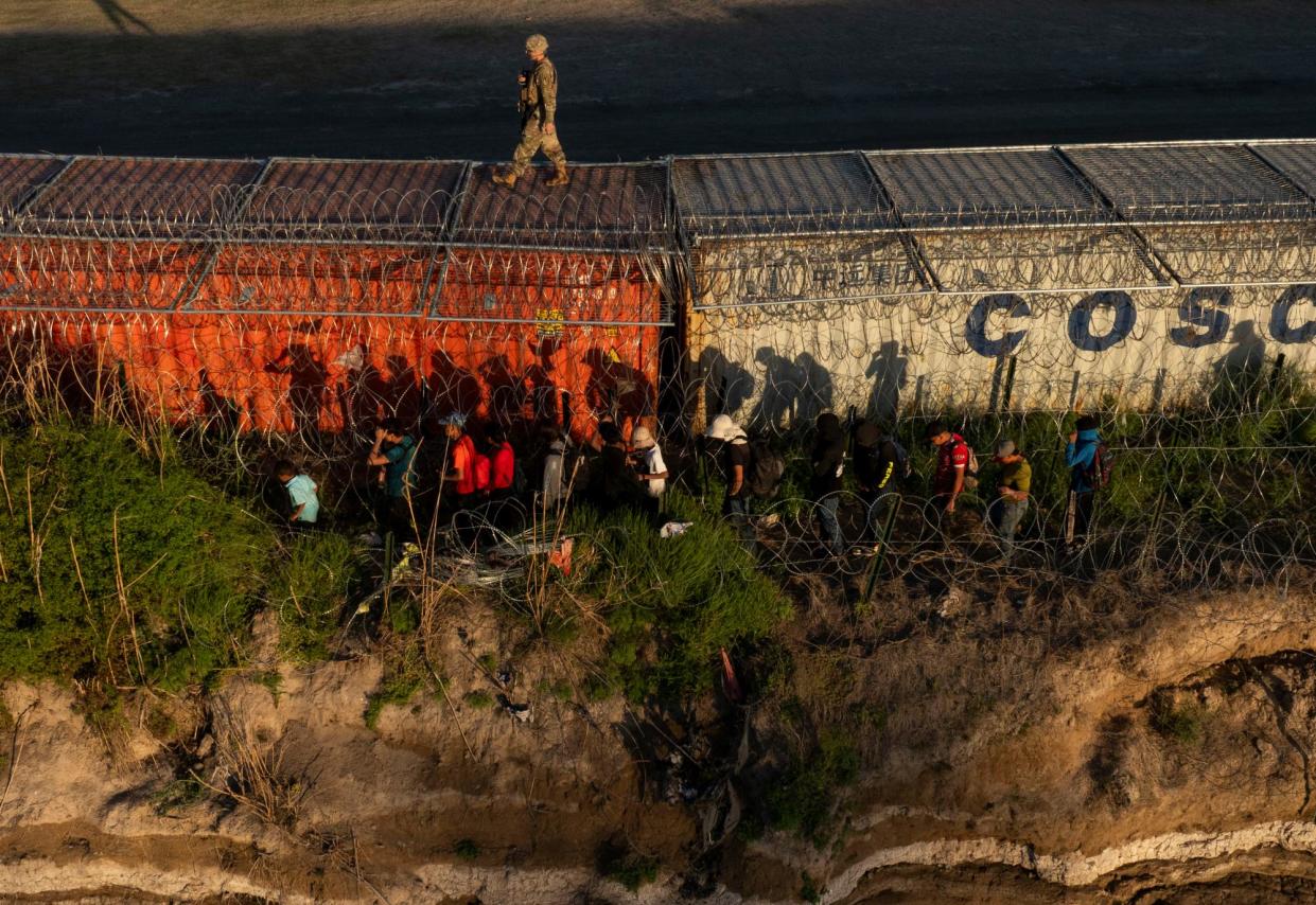 <span>A national guardsman patrols the US-Mexico border atop a shipping container.</span><span>Photograph: Michael Gonzalez/The Guardian</span>